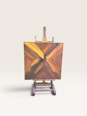 un petit chevalet sur lequel est posé un tableau, posé sur une surface blanche