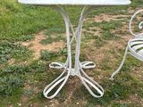 an image of a white table and two chairs in a field