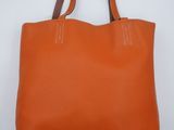 un sac fourre-tout en cuir orange sur fond blanc