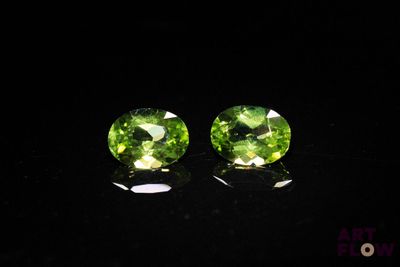 a pair of green tourmaline gems on a black surface