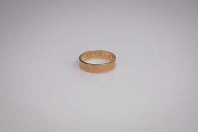 gros plan d'une bague en or sur une surface blanche