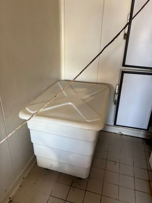 a white trash can in the corner of a room