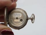a person holding a silver pocket watch in their hand