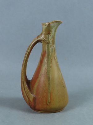 a brown and orange pitcher with a handle on a table