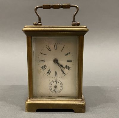 a small brass clock with roman numerals on the face