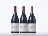 three bottles of red wine are lined up on a table