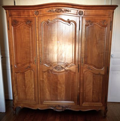 a large wooden armoire in the corner of a room