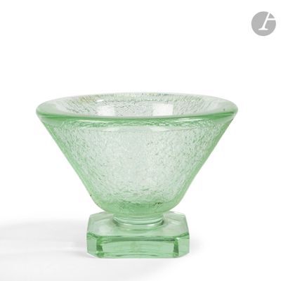 un bol en verre vert posé sur un socle, sur une surface blanche