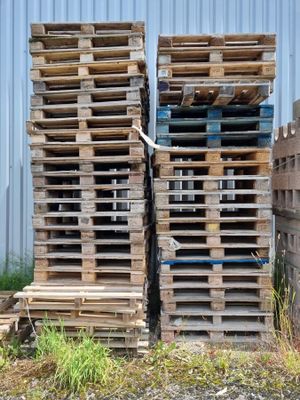 de nombreuses palettes en bois empilées les unes sur les autres devant un bâtiment