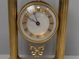 une image représentant une horloge dorée dont le cadran est orné de chiffres romains