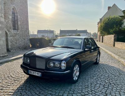 une photo d'une voiture noire garée dans une rue pavée