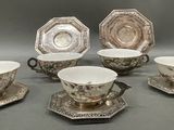 six pieces of silver and white tea cups and saucers on a table