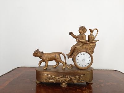 une horloge en bronze sur laquelle est représentée une figurine représentant un homme et un chien