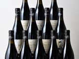 six bouteilles de vin sont alignées sur une table en bois
