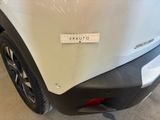 the rear end of a white car with a sticker on it ' s bumper