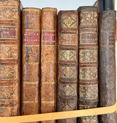 several old books are lined up on a shelf in a library