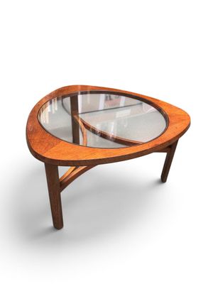 an oval coffee table with a glass top and wooden legs