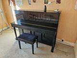 a piano in the corner of a room with a stool