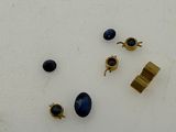 three pairs of gold and blue stone earrings on a white surface