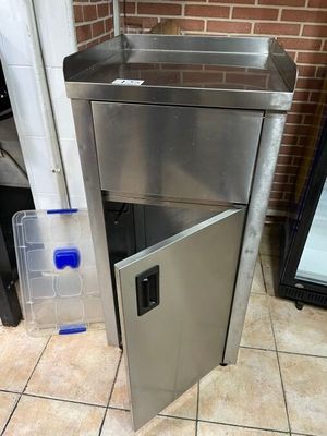 a stainless steel sink with a door open on a tiled floor