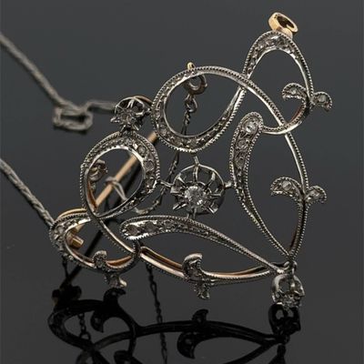 un gros plan d'un collier en or et en argent posé sur une surface noire