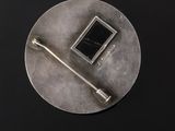 silver plate with a black square on it and a metal handle