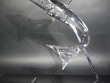 sculpture en verre transparent, reposant sur un socle incurvé posé sur une surface noire