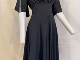 une robe noire posée sur un mannequin, devant un fond blanc