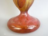 un vase rouge orné d'une feuille, posé sur un fond blanc