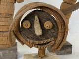 a sculpture of a face made out of wood on a stand