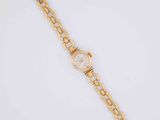a close up of a gold watch on a white surface