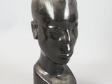 a black sculpture of a man ' s head on a white surface