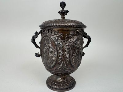 an ornate silver vase with a lid and handles on a white background