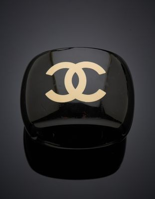 une bague noire et dorée ornée d'un logo blanc