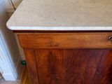 a wooden cabinet with a marble top in the corner of a room