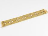 an image of a gold metal bracelet with holes on it