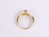 a close up of a gold ring with a red stone on it