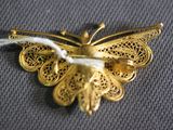 a gold butterfly brooch on a gray cloth