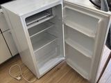 an open refrigerator sitting in a kitchen next to a dining room table