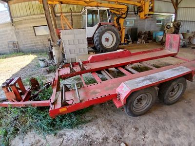 une remorque rouge avec un tracteur en arrière-plan
