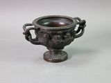a bronze vase with a lion head on it