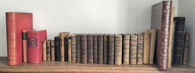 de nombreux livres anciens sur une étagère, avec une horloge au-dessus