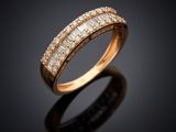 a gold ring with baguets and diamonds on a black background