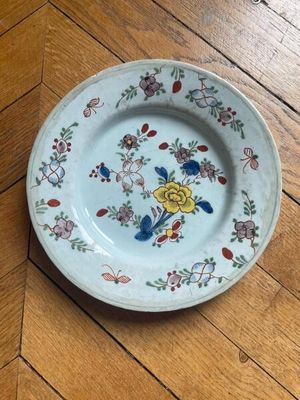 a plate with a flower design on it on a wooden floor