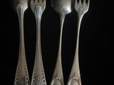 trois cuillères en argent et deux cuillères en argent sur un fond noir