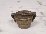brass plated container with a handle on a marble surface