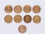 six types différents de pièces d'or disposées en triangle sur une surface blanche