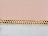 un gros plan d'un bracelet à chaîne en or posé sur une surface en marbre