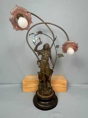 statue en bronze représentant une femme tenant une fleur et une lampe