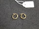 une paire de petites boucles d'oreilles en or en forme d'anneaux sur un fond noir